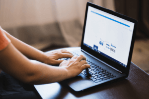 Close-up of a digital marketer typing on a black laptop keyboard at a desk